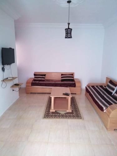 ein Wohnzimmer mit 2 Betten und einem Tisch in der Unterkunft Appartement Hammamet in Hammamet