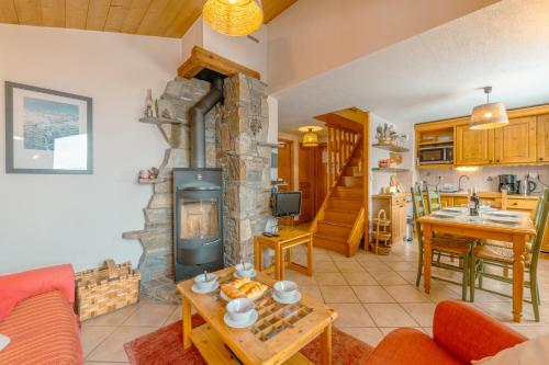 a living room with a stone fireplace and a kitchen at 3 chambres - Plan des Reines - Happy Rentals in Chamonix