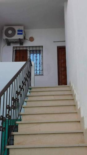 eine Treppe in einem Haus mit einem Fenster und einem Ventilator in der Unterkunft Appartement Hammamet in Hammamet