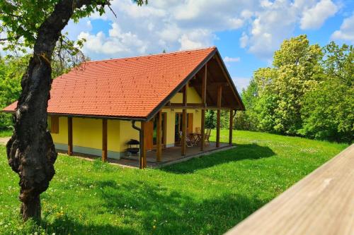 a yellow cottage with a red roof in a green field at Forester's Hut With Whirlpool & Sauna - Happy Rentals in Dol pri Hrastniku