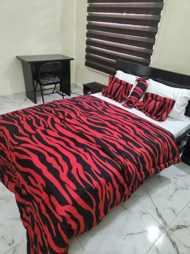 a bed with a red and black zebra blanket at LA VIVA AIRBNB in Abuja