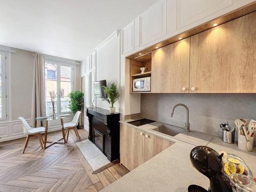 une cuisine avec des armoires blanches, une table et un évier dans l'établissement Camilla, à Troyes