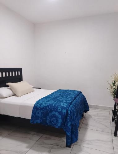 a bedroom with a bed with a blue blanket on it at Hermosos Departamentos in Cozumel