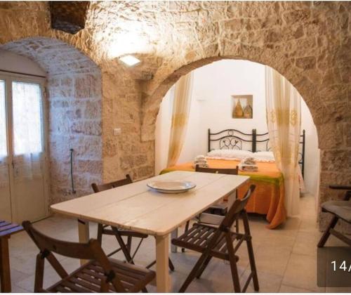 einen Tisch und Stühle in einem Zimmer mit einem Bett in der Unterkunft Trullo Masiello in Putignano
