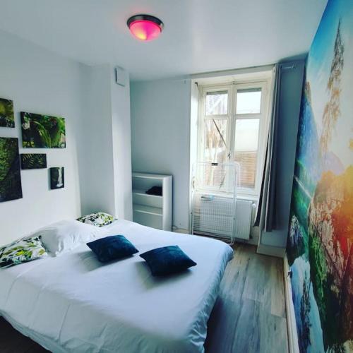 une chambre avec un grand lit blanc avec des oreillers bleus dans l'établissement Le Donjon de Mulhouse, à Mulhouse