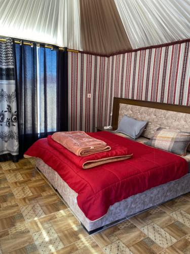 a bedroom with a bed with a red blanket on it at WADI Rum STARLIGHT CAMP in Wadi Rum