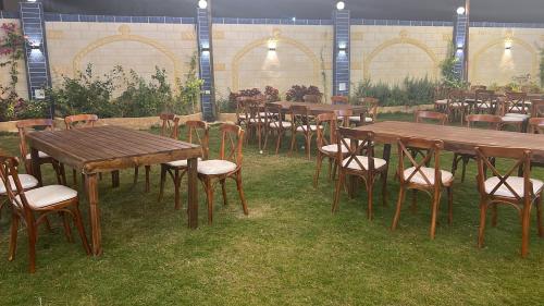 een groep houten tafels en stoelen in het gras bij فيلا الواحة للحفلات والمناسبات بالعجمي/أبو يوسف in Alexandrië
