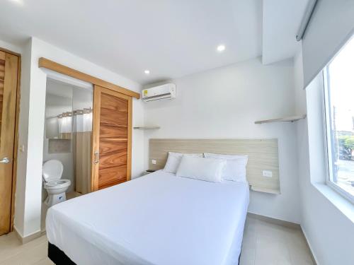 1 dormitorio con cama blanca y ventana en Stanza Hotel Monteria, en Montería