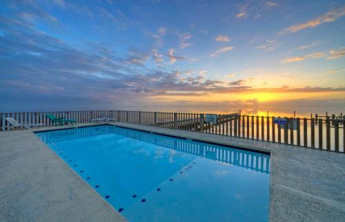 a swimming pool in front of the ocean at sunset at Laguna Village Paradise 2 Home Buyout On Water in Padre Island