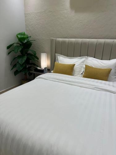 a large white bed with two pillows and a plant at Three Bedroom furnished apartment in north Riyadh in Riyadh