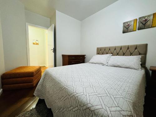 um quarto com uma cama grande e um edredão branco em MRG - Ensolarado 2D - Centro de Gramado em Gramado