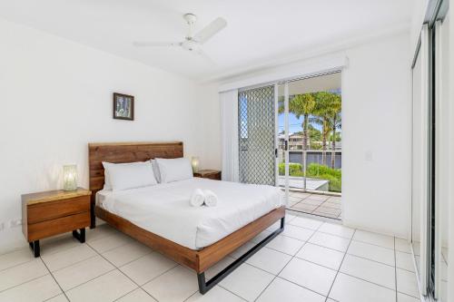 1 dormitorio con 1 cama y puerta corredera de cristal en Tingeera Bespoke Beachfront Apartments en Hervey Bay