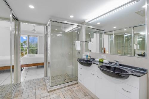 a bathroom with two sinks and a shower at Tingeera Bespoke Beachfront Apartments in Hervey Bay