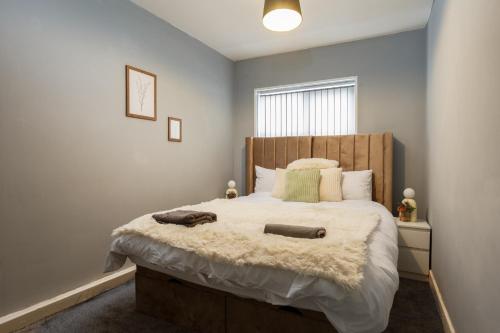 a bedroom with a large bed with a wooden headboard at Lovely Getaway Apartment: Two-Bedroom in Rotherham in Rotherham