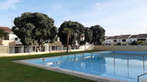 a swimming pool in a yard with trees in the background at Swim&Beach Condominio Torreira in Torreira