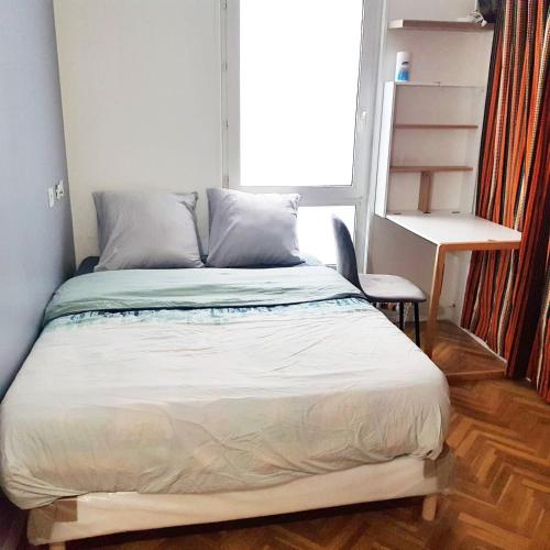 Bett in einem Zimmer mit einem Schreibtisch und einem Fenster in der Unterkunft Beautiful and Cosy Room in Villejuif