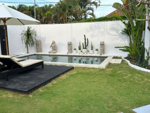 einen Hinterhof mit einem Pool mit einem Stuhl und einem Kaktus in der Unterkunft Villa Curves Bali in Seminyak
