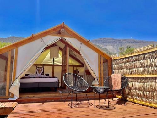a tent with a bed and two chairs on a deck at La villa Glamping in San José de Maipo