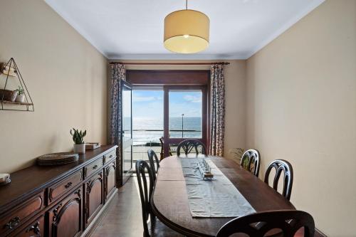 a dining room with a table and chairs and a window at Ombak Apúlia - Sea view in Apúlia