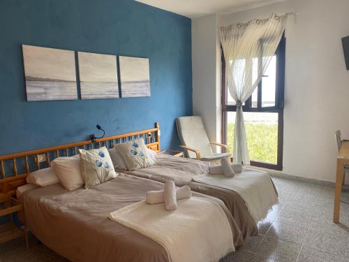 エルミグアにあるApartamentos Playaのベッドルーム1室(青い壁のベッド2台、窓付)