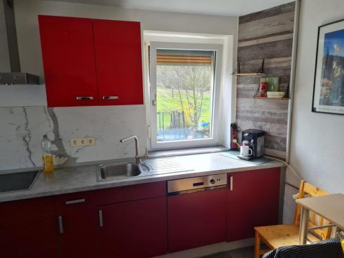 una cocina con armarios rojos y una ventana en Husic Immobilien und Handwerkerservice, en Rimbach