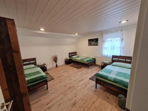 RimbachにあるHusic Immobilien und Handwerkerserviceのベッド3台が備わるウッドフロアの客室です。