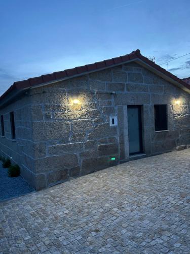 ein Steinhaus mit einer Ziegelwand mit einer Tür in der Unterkunft Casa da Ti Mília in Trancoso