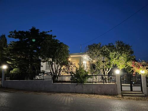 a white house with a fence and trees at night at Εξοχικό elia lakonias in Elia Laconias