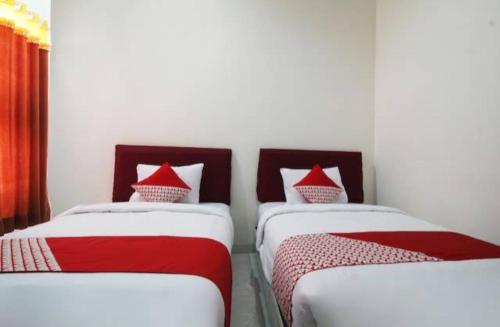 two beds in a room with red and white sheets at Wisma Alda in Kedaton