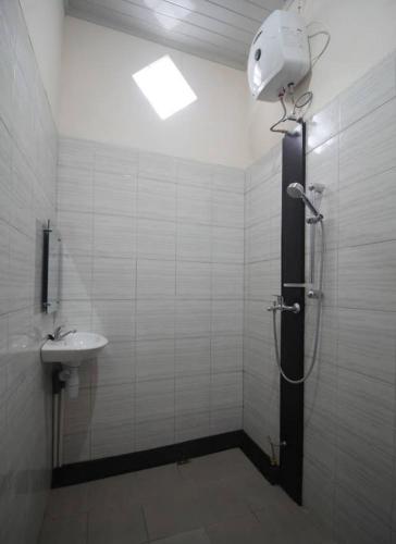 een badkamer met een douche en een wastafel bij Wisma Alda in Kedaton