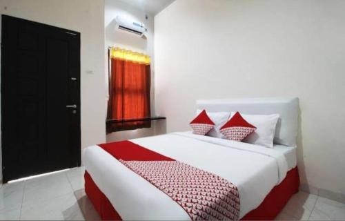 a bedroom with a large bed with red and white pillows at Wisma Alda in Kedaton