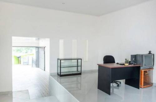 an office with a desk and a tv in a room at Wisma Alda in Kedaton