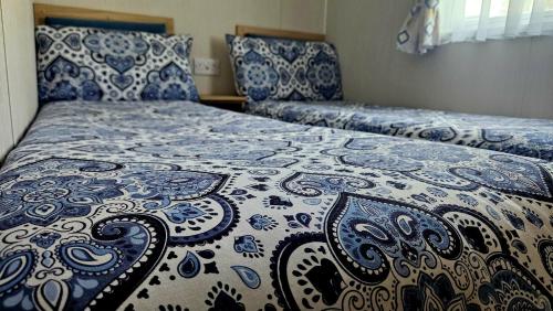 Charming 3-Bed Caravan in Colchester Mersea island في كولشستر: غرفة نوم بسرير لحاف ازرق وبيض