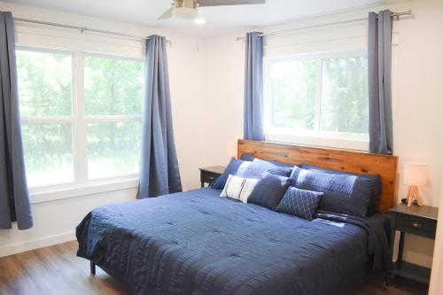 - une chambre avec un lit doté de draps bleus et de fenêtres dans l'établissement 5 STAR King Bed Lux Cabin•Netflix & Hulu 4K UHD TV, à Broken Bow
