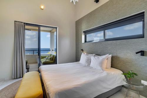 a bedroom with a large bed with a large window at SENSES Boutique Hotel & Apartments in Kralendijk