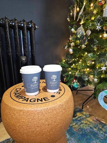 Harmony Cottage في إغلنتون: كوبين قهوة جالسين فوق شجرة عيد الميلاد