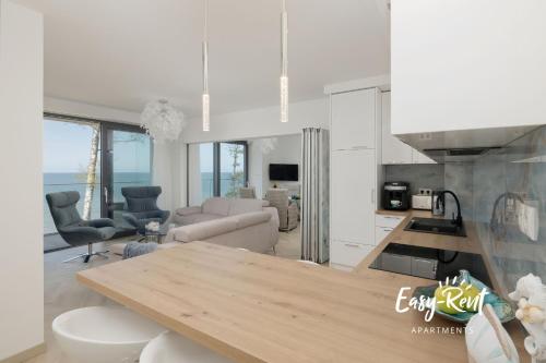 cocina blanca y sala de estar con mesa en Double Blue Bien - Easy-Rent Apartments bezpośrednio przy plaży, en Rewal