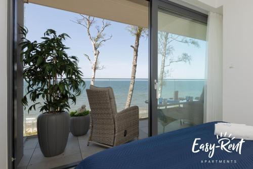 ein Schlafzimmer mit Bett und Blick auf das Meer in der Unterkunft Double Blue Bien - Easy-Rent Apartments bezpośrednio przy plaży in Rewal