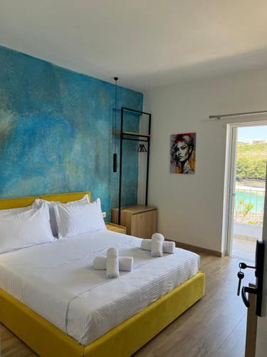 EMAAR Hotel Ksamil - BEACHFRONT , Newly Renovated في كساميل: غرفة نوم بسرير ابيض مع لوحة على الحائط