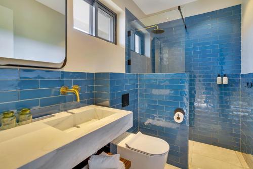a blue tiled bathroom with a sink and a toilet at SENSES Boutique Hotel & Apartments in Kralendijk