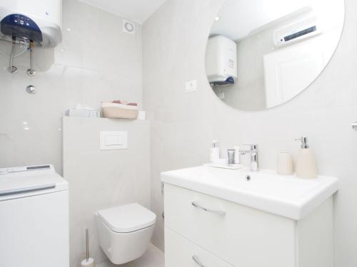 ein weißes Badezimmer mit einem Waschbecken und einem Spiegel in der Unterkunft Apartman 4* Ester in Rovinj