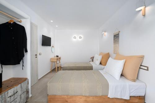 a bedroom with two beds and a tv on a wall at Electra Suites & Spa in Perivolos
