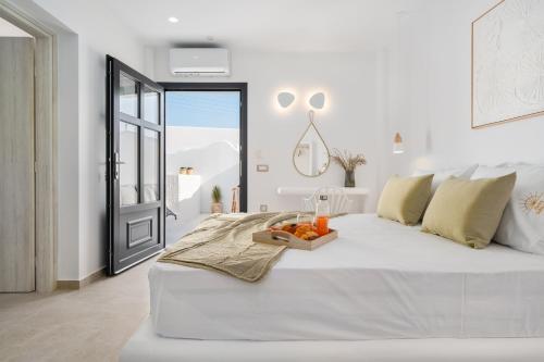 een witte slaapkamer met een bed en een dienblad met fruit erop bij Electra Suites & Spa in Perivolos