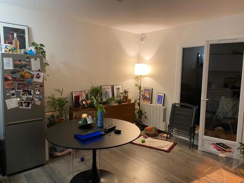 sala de estar con mesa y nevera en Charmant appartement avec terrasse privée, en Fontenay-sous-Bois