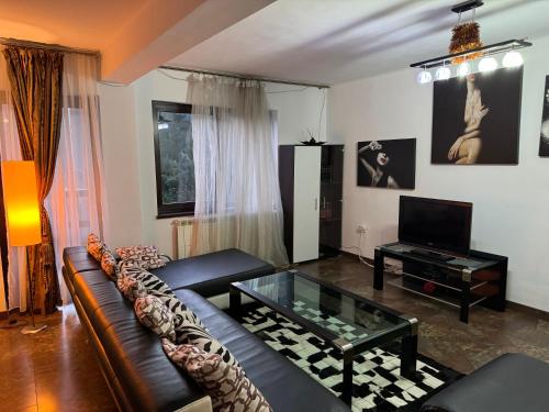 uma sala de estar com um sofá e uma mesa de vidro em Vila Babylon em Predeal