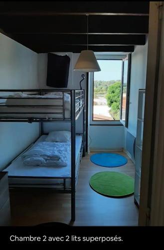 une chambre avec deux lits superposés et une fenêtre dans l'établissement La maison du marais, à Grand-Village-Plage
