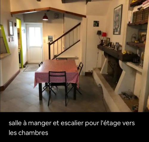 une table et des chaises dans une pièce avec un escalier dans l'établissement La maison du marais, à Grand-Village-Plage