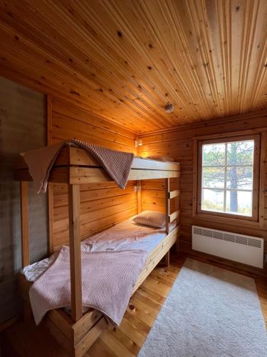 ein Schlafzimmer mit einem Bett in einer Holzhütte in der Unterkunft Villa Aiku in Leppäjärvi