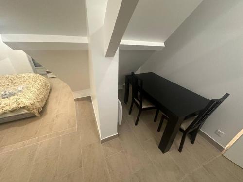 einen schwarzen Tisch und einen Stuhl in einem Zimmer mit einem Bett in der Unterkunft Studio dans une maison 2/3 in Aulnay-sous-Bois