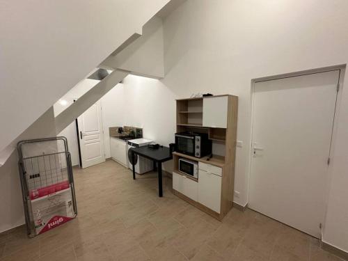 Zimmer mit einer Küche mit einer Mikrowelle und einem Tisch in der Unterkunft Studio dans une maison 2/3 in Aulnay-sous-Bois
